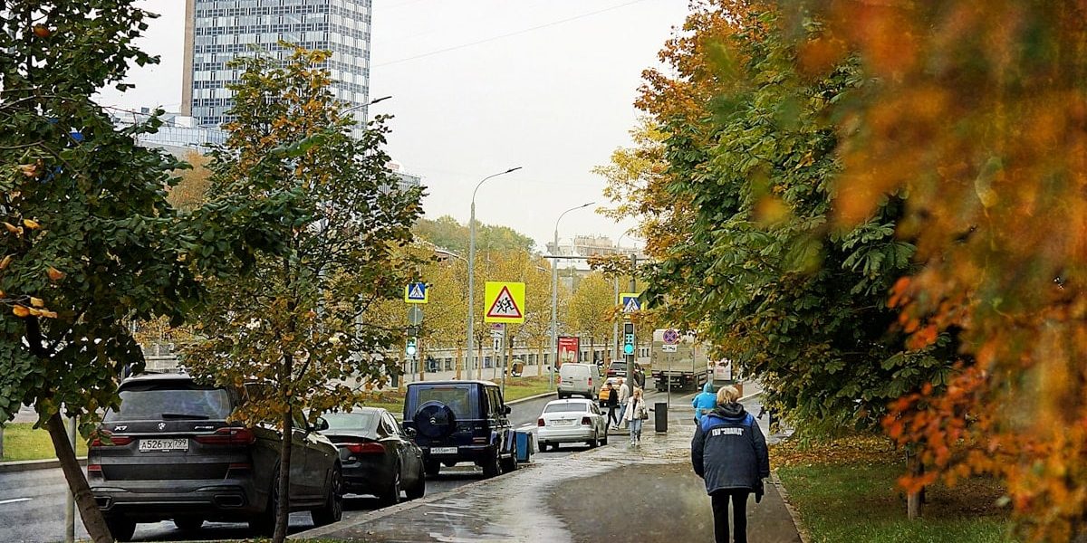 Autumn street with cars and a pedestrian