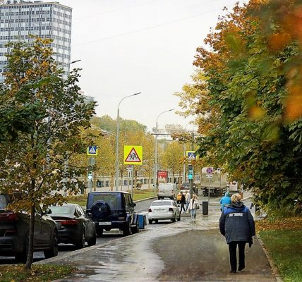 Autumn street with cars and a pedestrian