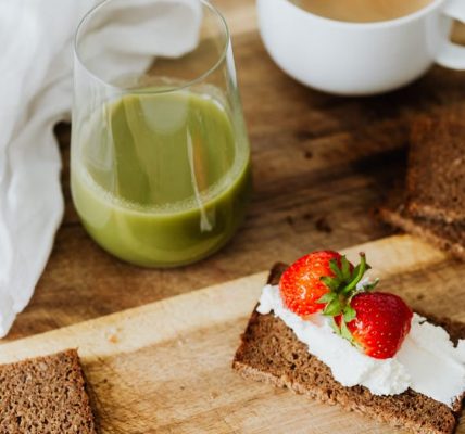 Start your day with a nutritious breakfast featuring rye toast with cream cheese and strawberries, paired with green juice and coffee.